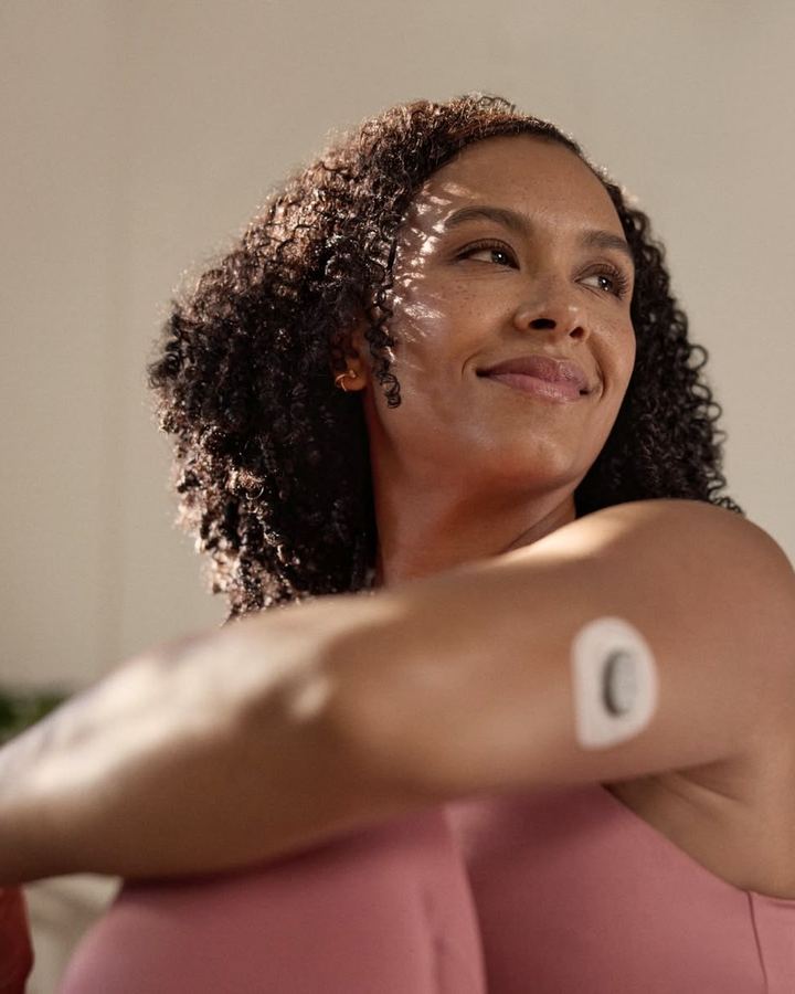 Woman with a continuous glucose monitor on her arm.