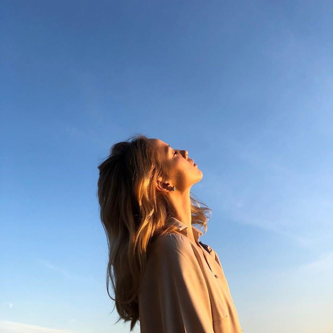 A woman in profile against a clear evening sky, face lifted to the last of the light