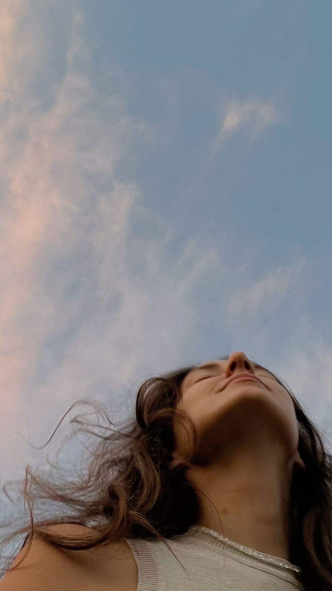 A woman lying back with her face lifted to a pale evening sky.